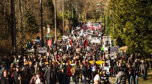 Large crowd marching with signs and banners opposing Trans Mountain